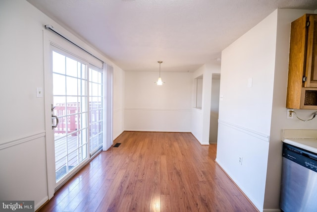 unfurnished dining area featuring baseboards and light wood finished floors