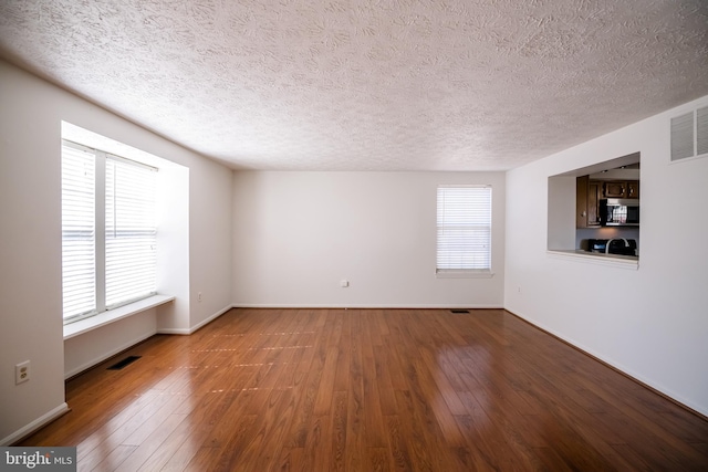 spare room featuring hardwood / wood-style flooring, plenty of natural light, and visible vents