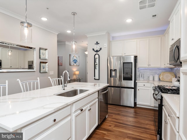 kitchen featuring decorative light fixtures, a center island with sink, stainless steel appliances, visible vents, and a sink