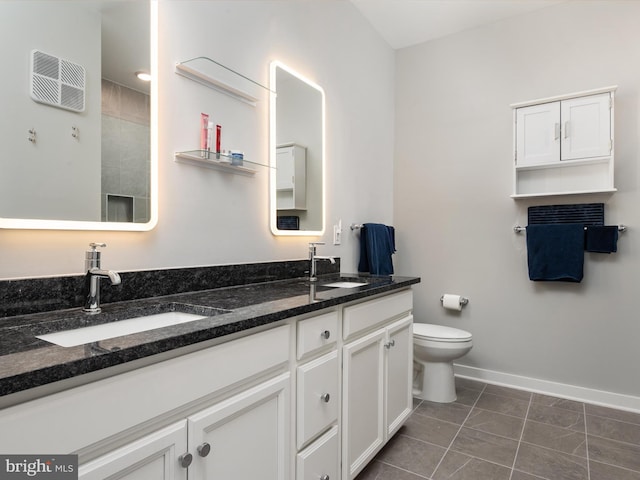 full bathroom with double vanity, a sink, toilet, and baseboards