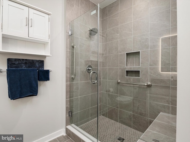 full bathroom with a stall shower and baseboards