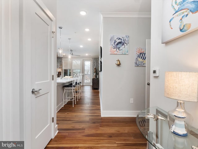 corridor with crown molding, baseboards, dark wood-style flooring, and recessed lighting