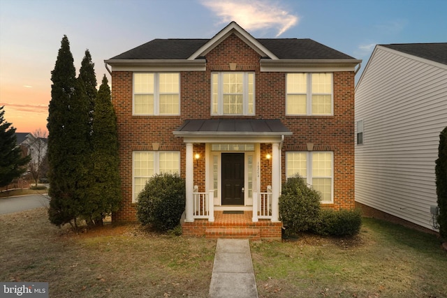 view of front of house with a yard, brick siding, and a shingled roof