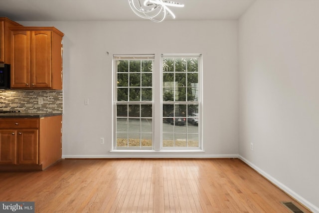 unfurnished dining area with baseboards, visible vents, and light wood-style floors