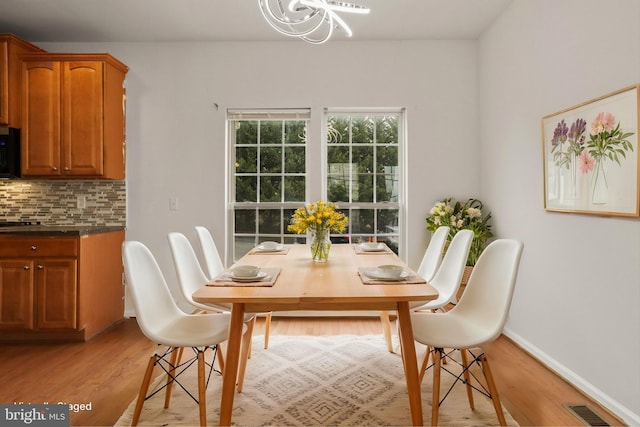 dining space with baseboards, visible vents, and light wood-style floors