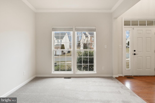 entrance foyer with baseboards, crown molding, visible vents, and a wealth of natural light