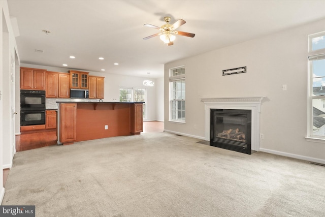 unfurnished living room featuring light carpet, baseboards, a fireplace with flush hearth, and recessed lighting