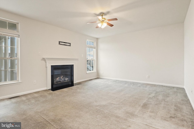 unfurnished living room with a fireplace with flush hearth, visible vents, carpet floors, and baseboards