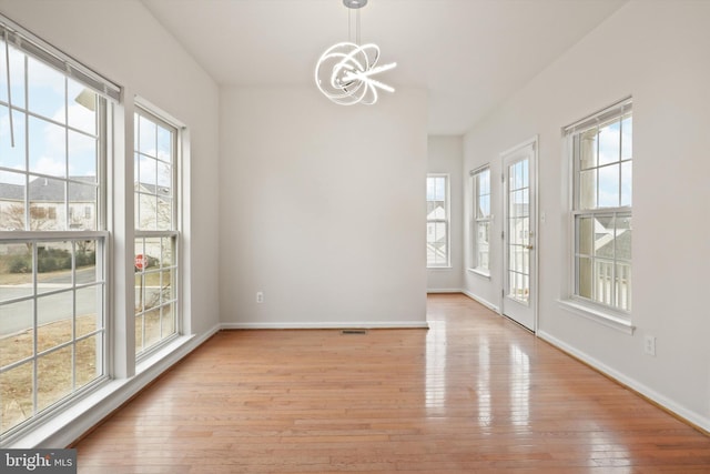 interior space with an inviting chandelier, light wood-style flooring, and baseboards