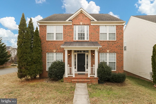 view of front of property featuring a front yard, brick siding, and roof with shingles