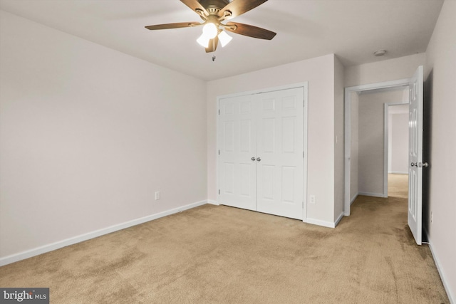 unfurnished bedroom featuring light carpet, a closet, a ceiling fan, and baseboards