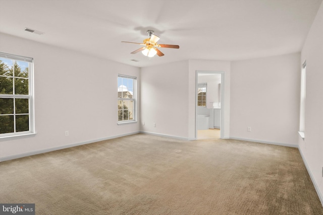 spare room featuring baseboards, a ceiling fan, visible vents, and light colored carpet