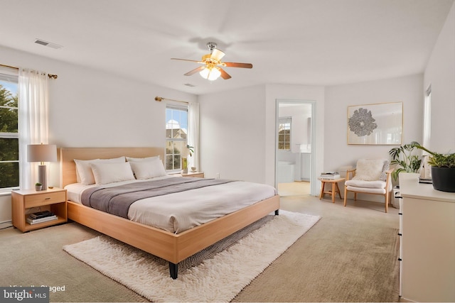 bedroom featuring light carpet, a ceiling fan, visible vents, and connected bathroom