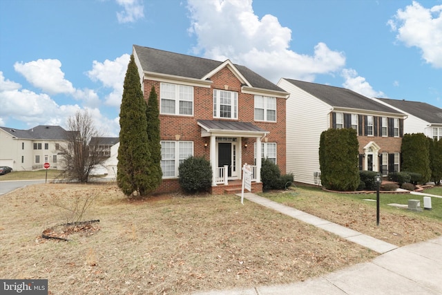 colonial house featuring brick siding, a front yard, and a residential view