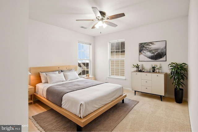 bedroom featuring baseboards, visible vents, a ceiling fan, and light colored carpet