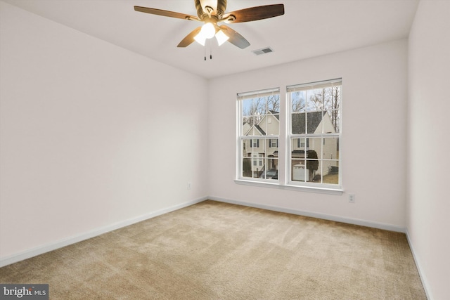 spare room featuring baseboards, a ceiling fan, visible vents, and light colored carpet