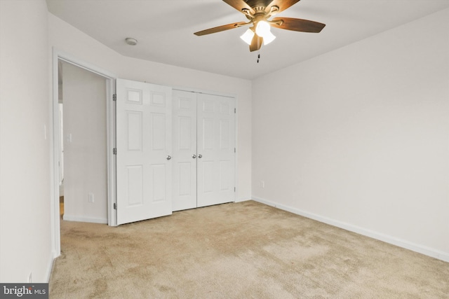 unfurnished bedroom featuring light carpet, a closet, a ceiling fan, and baseboards