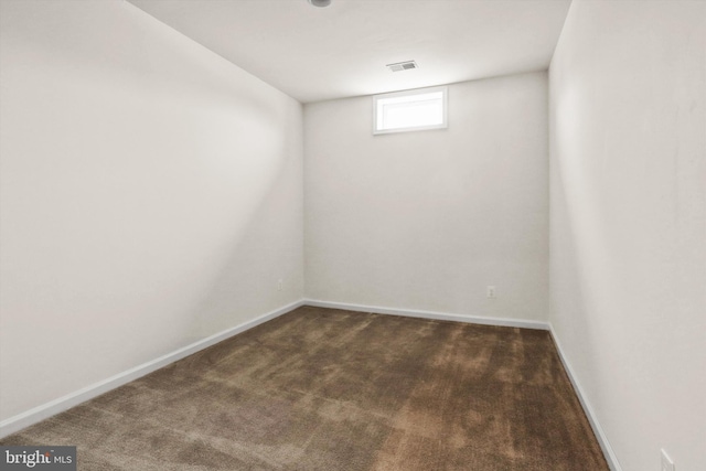 basement featuring baseboards, visible vents, and dark colored carpet