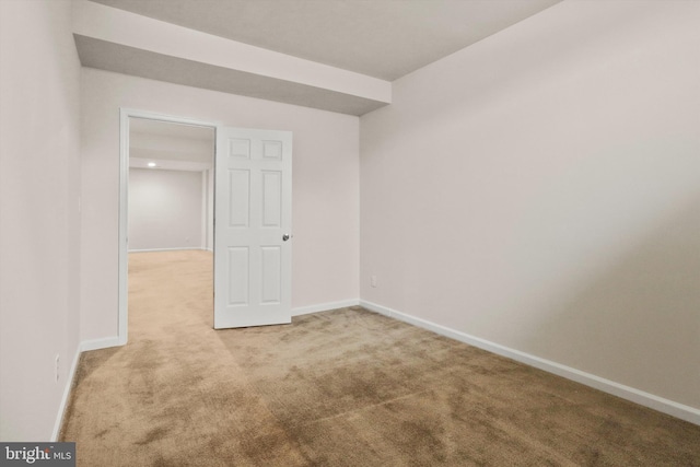 unfurnished room with baseboards and light colored carpet