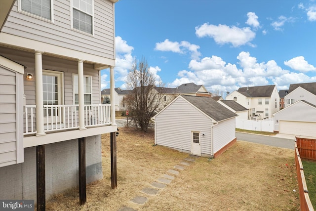 view of yard featuring an outdoor structure, a balcony, and a residential view