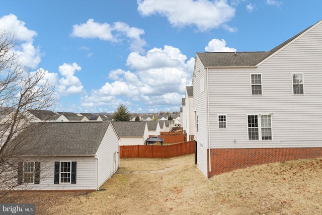 view of property exterior with a yard, roof with shingles, and fence