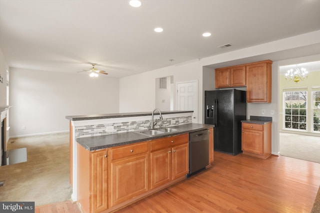 kitchen with dark countertops, brown cabinetry, a sink, a kitchen island, and black appliances