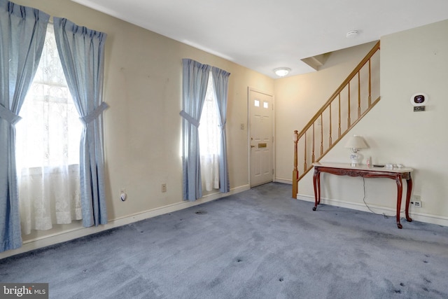 carpeted entrance foyer with stairway and baseboards