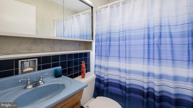 bathroom featuring toilet, tasteful backsplash, and vanity