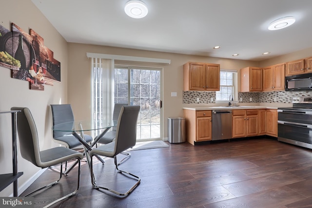 kitchen with dark wood-style floors, tasteful backsplash, light countertops, appliances with stainless steel finishes, and a sink