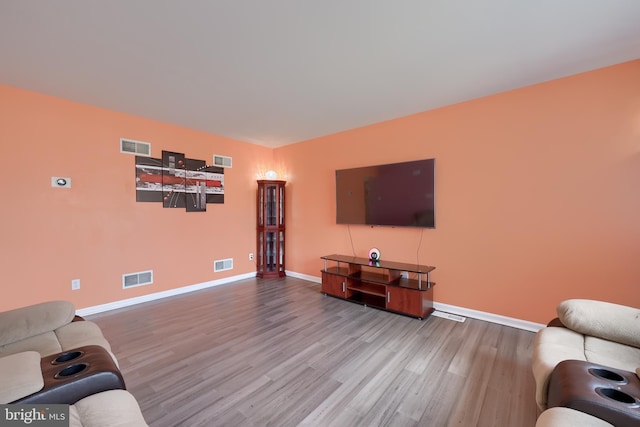 living room with wood finished floors, visible vents, and baseboards