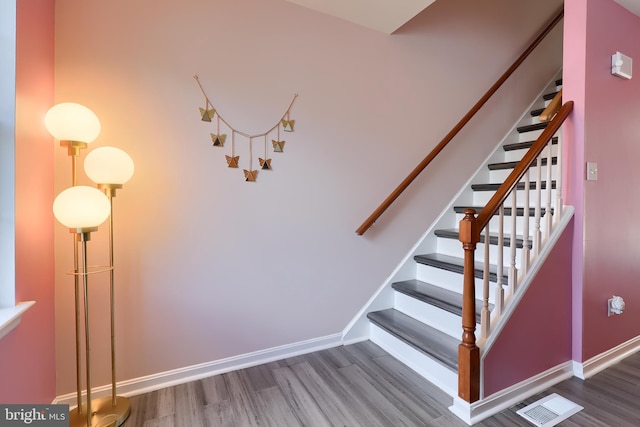 stairway with wood finished floors, visible vents, and baseboards