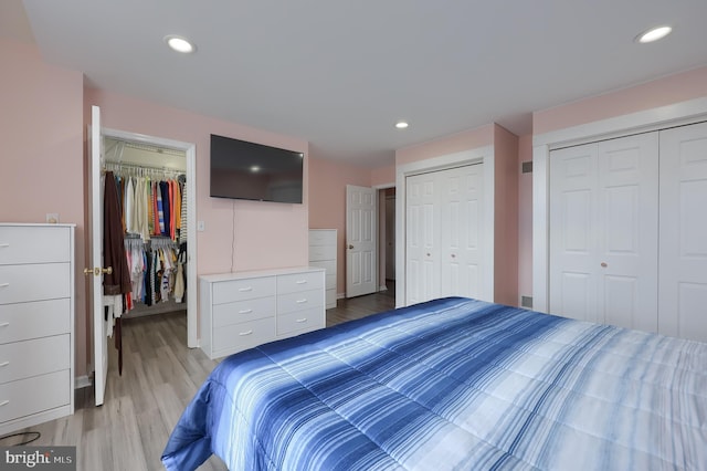 bedroom featuring light wood-style floors, a spacious closet, two closets, and recessed lighting