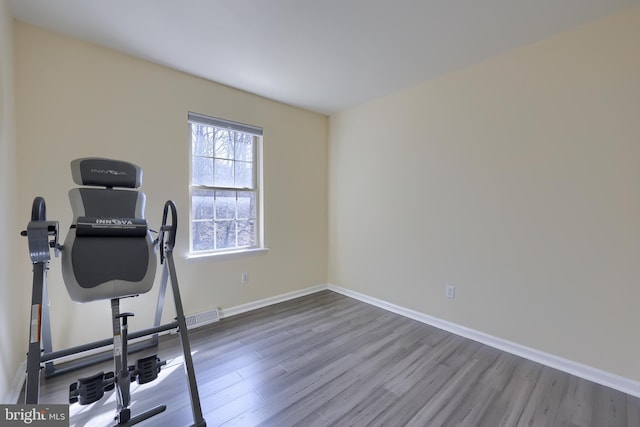 workout area featuring baseboards, visible vents, and wood finished floors