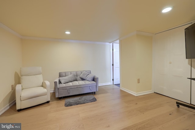 sitting room with baseboards, wood finished floors, and crown molding