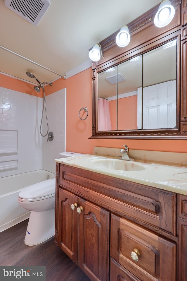 bathroom featuring visible vents, toilet, washtub / shower combination, vanity, and wood finished floors