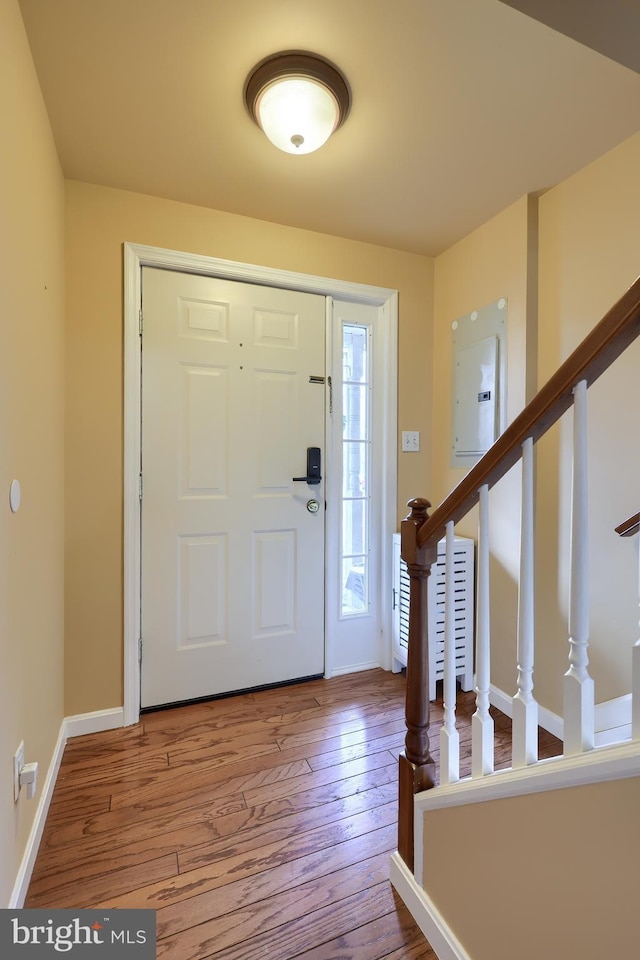 foyer featuring baseboards, electric panel, stairway, and hardwood / wood-style floors