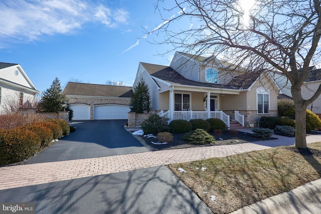 view of front of property with a garage, stone siding, a porch, and stucco siding