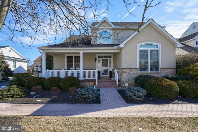 view of front of home featuring stone siding, covered porch, and stucco siding