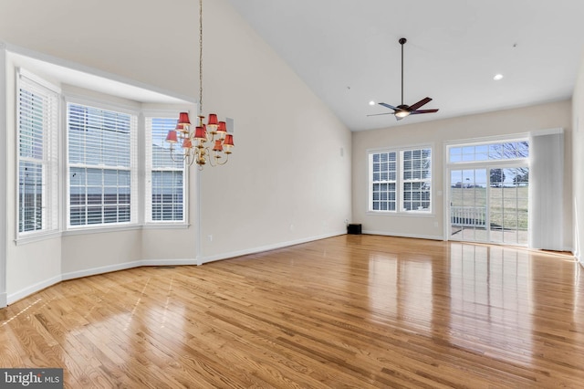 unfurnished living room with light wood finished floors, baseboards, recessed lighting, ceiling fan with notable chandelier, and high vaulted ceiling