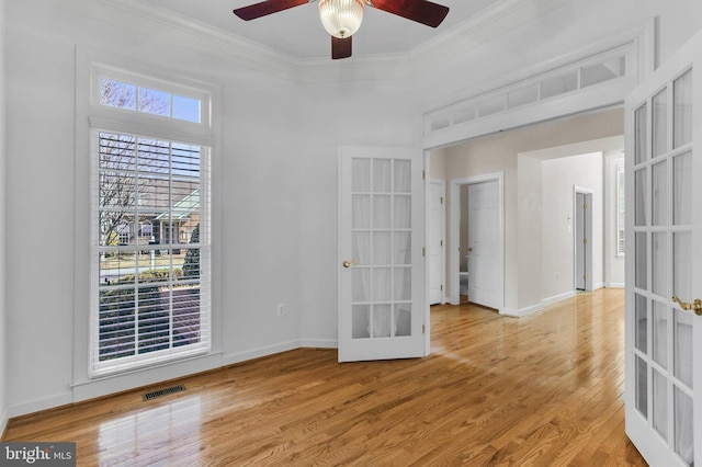 empty room featuring visible vents, baseboards, ornamental molding, french doors, and wood finished floors