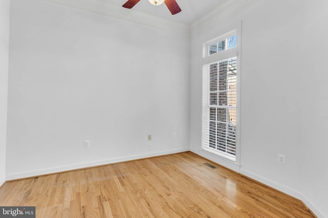 unfurnished room with a ceiling fan, wood finished floors, visible vents, baseboards, and ornamental molding