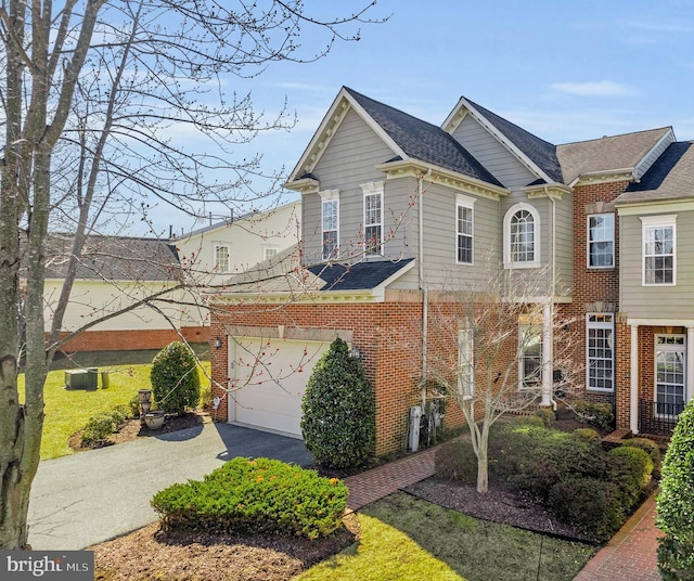 view of front of home with brick siding, an attached garage, driveway, and a shingled roof