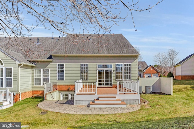 back of property featuring a deck, central AC unit, a lawn, and roof with shingles