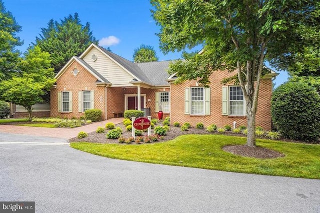 view of front of home featuring brick siding, driveway, and a front yard