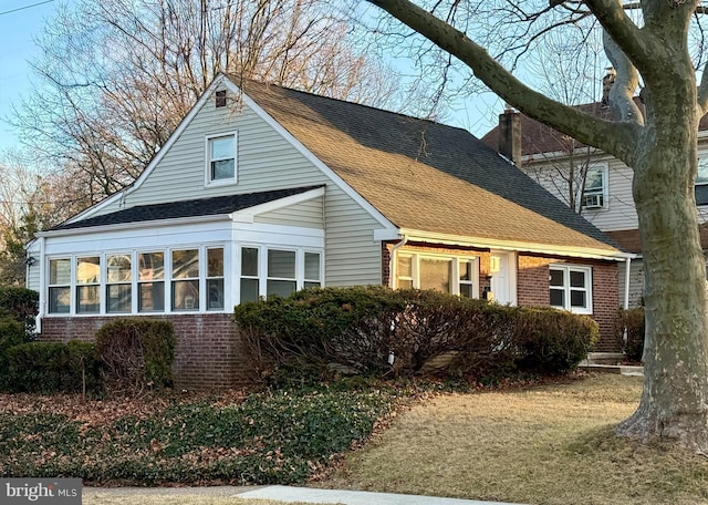 exterior space with roof with shingles, a chimney, and brick siding