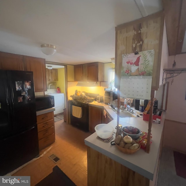 kitchen featuring visible vents, light countertops, brown cabinets, black appliances, and washer / clothes dryer