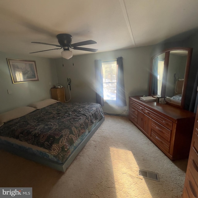 bedroom featuring a ceiling fan, light colored carpet, and visible vents
