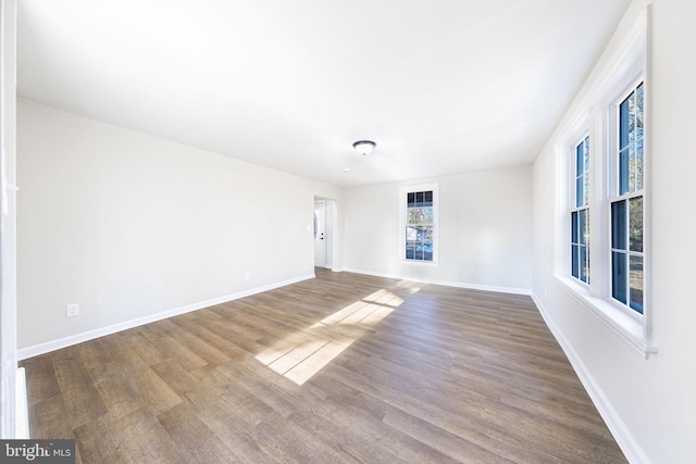 spare room with baseboards and wood finished floors