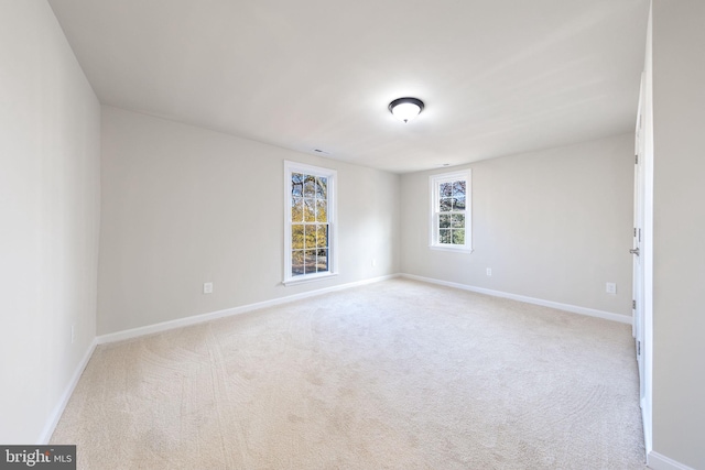 unfurnished room featuring baseboards and light colored carpet