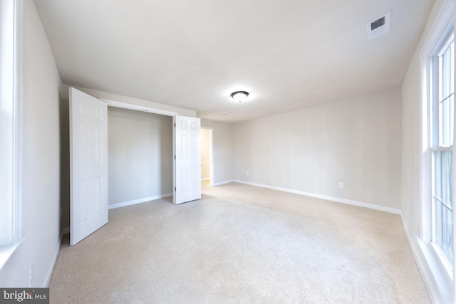 unfurnished bedroom with baseboards, visible vents, and light carpet